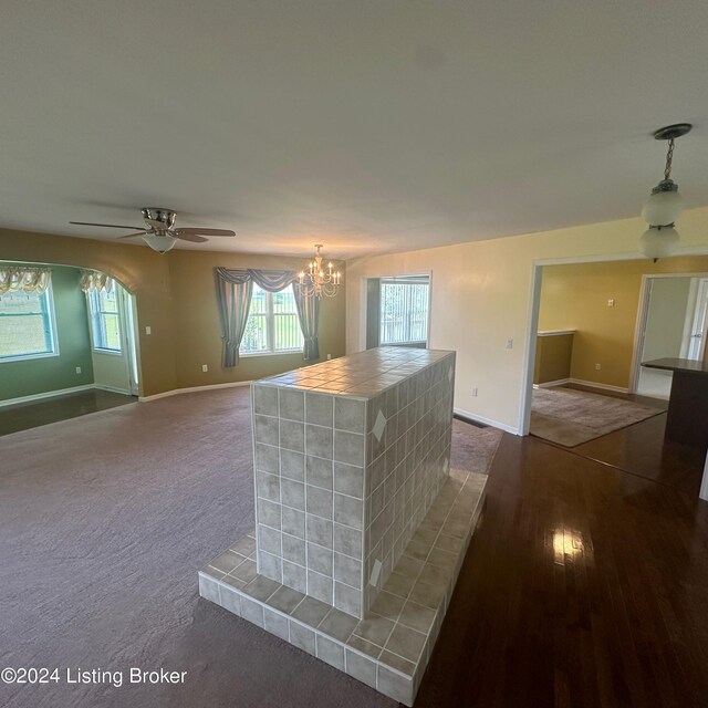 interior space with dark wood-type flooring and ceiling fan with notable chandelier