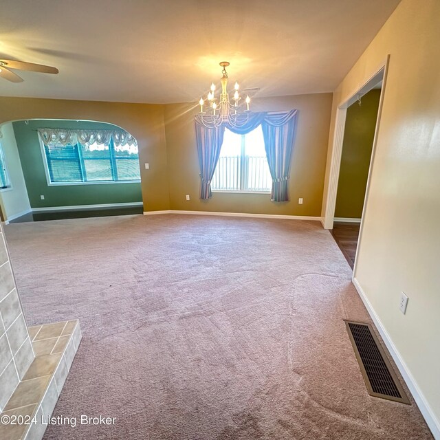 carpeted spare room with ceiling fan with notable chandelier