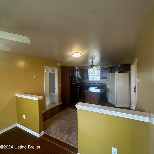 kitchen featuring white fridge with ice dispenser, ceiling fan, dark wood-type flooring, and kitchen peninsula