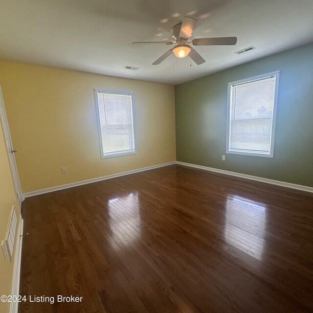 spare room featuring plenty of natural light, ceiling fan, and dark hardwood / wood-style flooring