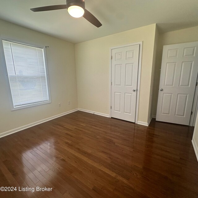 unfurnished bedroom with ceiling fan and dark wood-type flooring