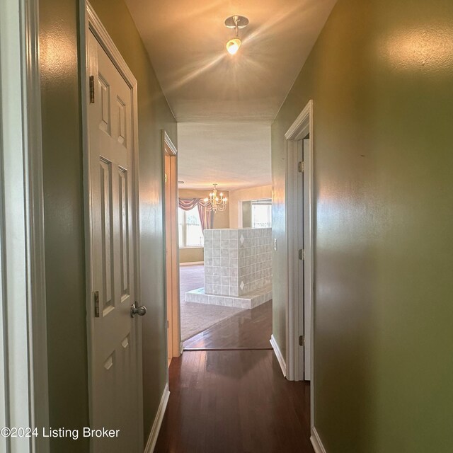 hall with dark hardwood / wood-style flooring and an inviting chandelier