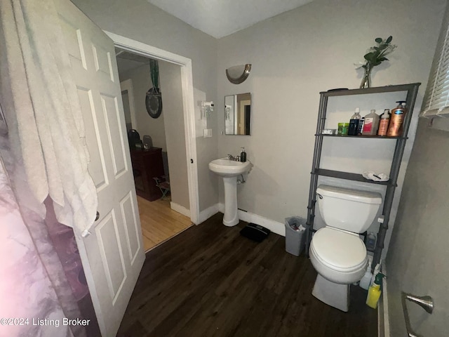 bathroom featuring toilet, a sink, baseboards, and wood finished floors