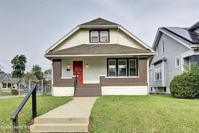 bungalow with covered porch and a front lawn