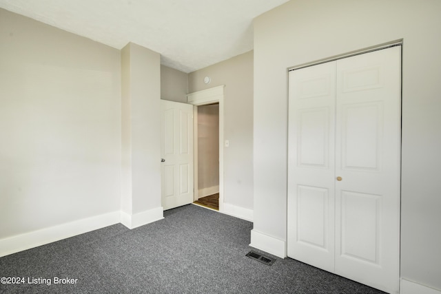 unfurnished bedroom featuring a closet and dark colored carpet