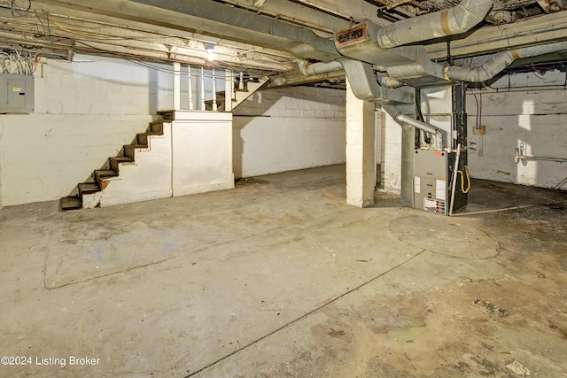 basement featuring electric panel and heating unit