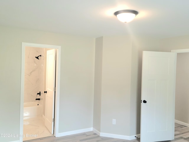 unfurnished bedroom featuring ensuite bathroom and light hardwood / wood-style floors