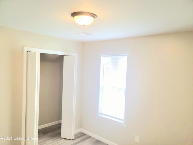 unfurnished bedroom with light hardwood / wood-style flooring and a closet