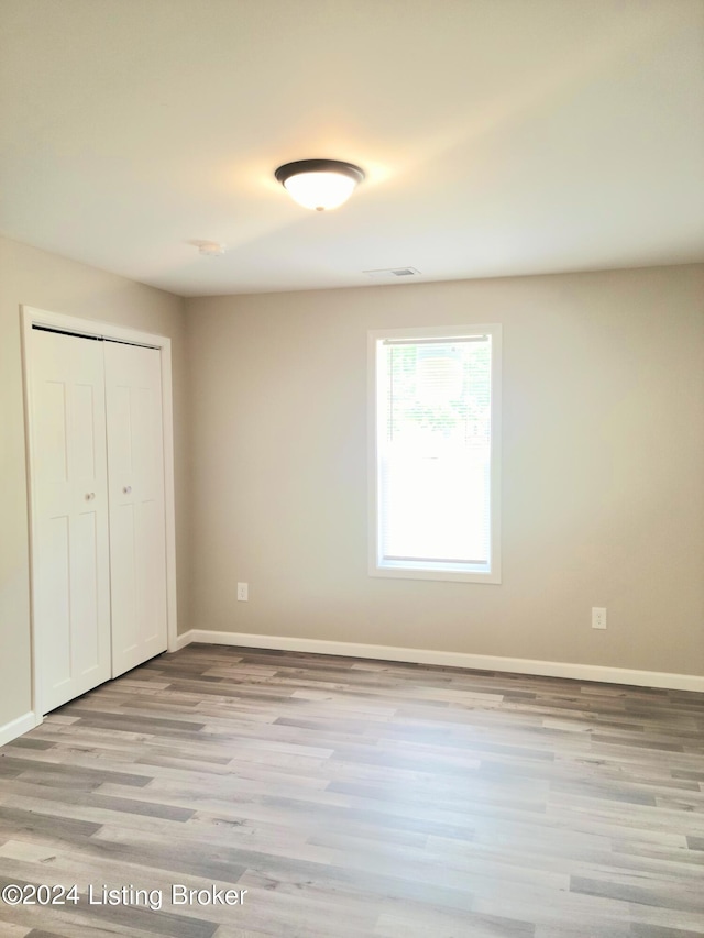 unfurnished bedroom with a closet and light hardwood / wood-style floors