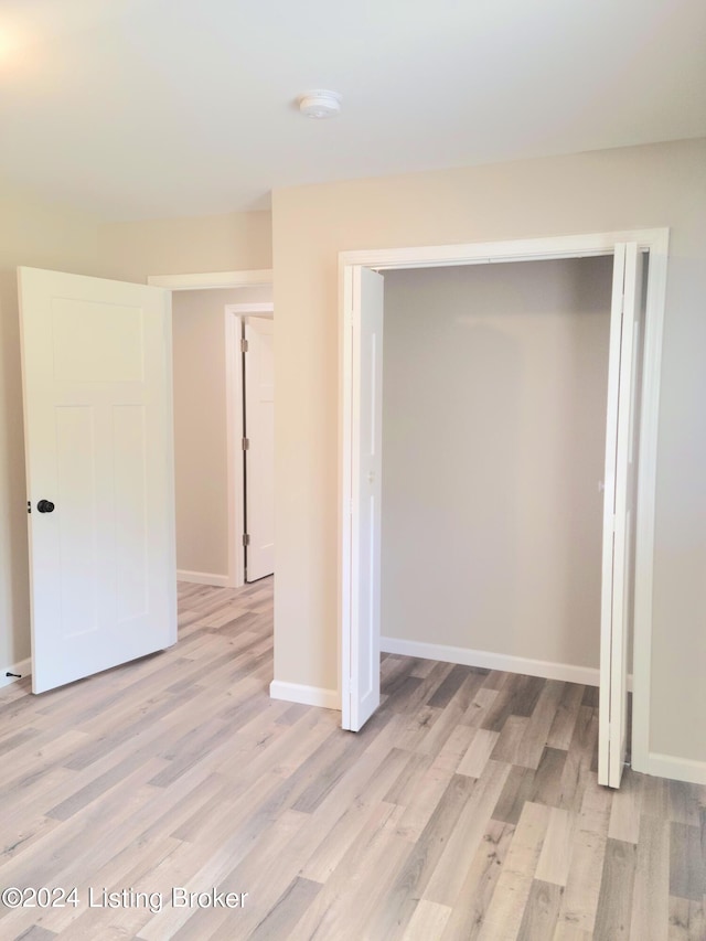 unfurnished bedroom with light hardwood / wood-style flooring and a closet