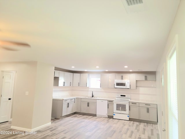 kitchen featuring white appliances, light hardwood / wood-style flooring, and sink