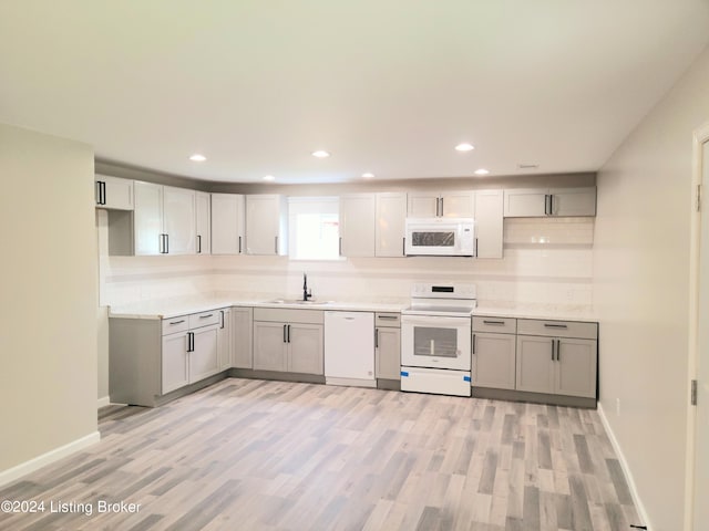 kitchen with white appliances, sink, gray cabinetry, and light hardwood / wood-style floors