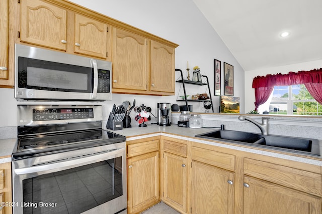 kitchen with sink, light brown cabinetry, appliances with stainless steel finishes, and vaulted ceiling