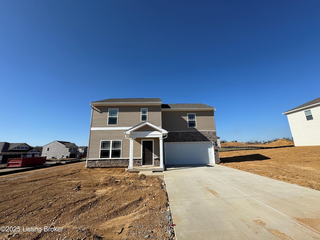 traditional home with a garage, stone siding, and concrete driveway