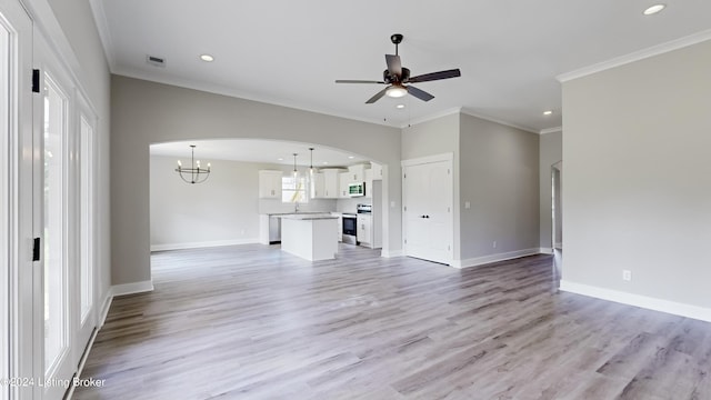 unfurnished living room with crown molding, ceiling fan with notable chandelier, and light wood-type flooring