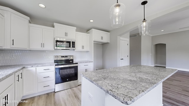 kitchen with white cabinetry, stainless steel appliances, a center island, and pendant lighting