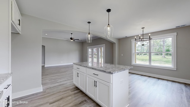 kitchen with light stone countertops, a kitchen island, and white cabinets