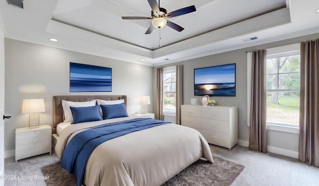 carpeted bedroom with a tray ceiling and ceiling fan