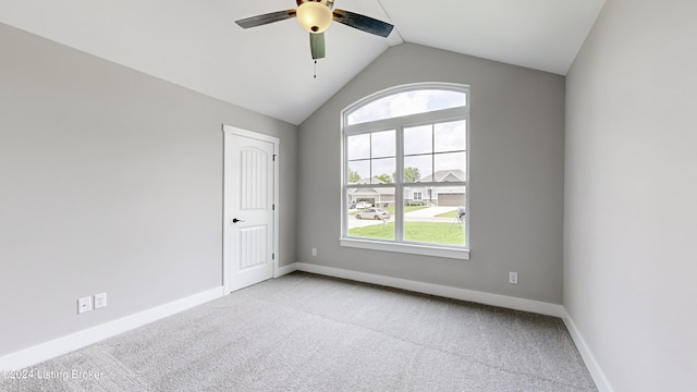 spare room with ceiling fan, lofted ceiling, and light carpet