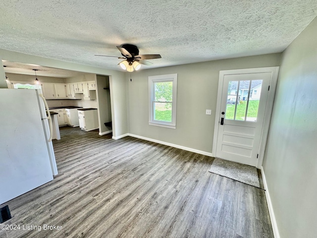 interior space with light hardwood / wood-style floors, plenty of natural light, white fridge, and white cabinetry