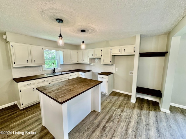 kitchen featuring white cabinets, sink, a kitchen island, hardwood / wood-style flooring, and decorative backsplash