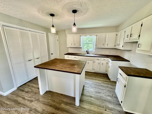 kitchen with pendant lighting, light hardwood / wood-style floors, a center island, and white cabinetry