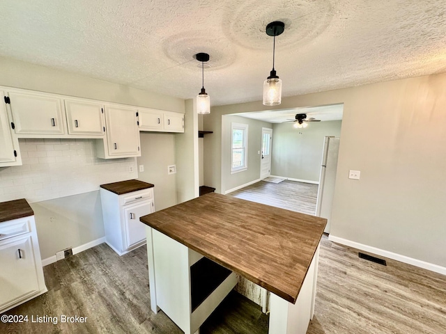 kitchen with white refrigerator, wood-type flooring, and white cabinetry