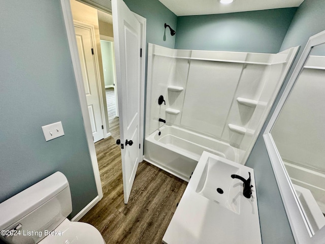 bathroom with shower / bathing tub combination, wood-type flooring, and toilet