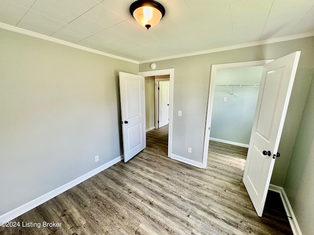 unfurnished bedroom featuring wood-type flooring, a closet, and ornamental molding