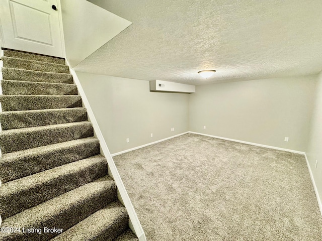 basement featuring carpet flooring and a textured ceiling