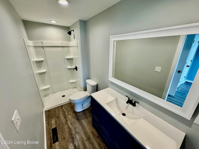 bathroom with walk in shower, hardwood / wood-style flooring, vanity, and toilet