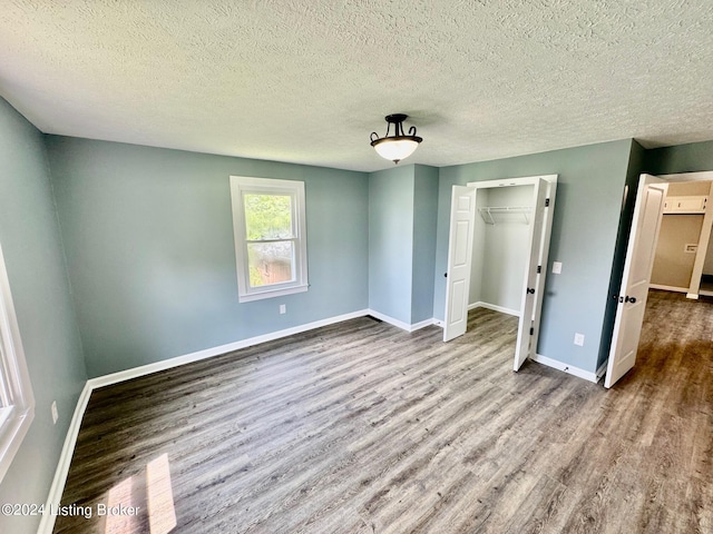 unfurnished bedroom with a textured ceiling, light wood-type flooring, and a closet