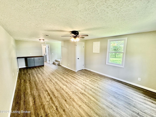 unfurnished living room featuring ceiling fan, a textured ceiling, and hardwood / wood-style floors