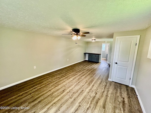 unfurnished living room featuring hardwood / wood-style flooring, ceiling fan, and a textured ceiling