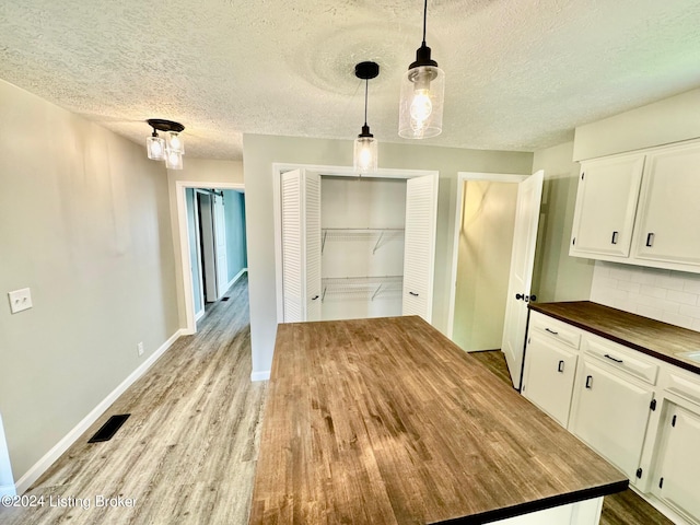 unfurnished dining area featuring a textured ceiling and light hardwood / wood-style floors