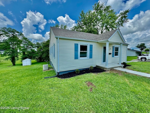 view of front of home with a storage shed, a front lawn, and central air condition unit