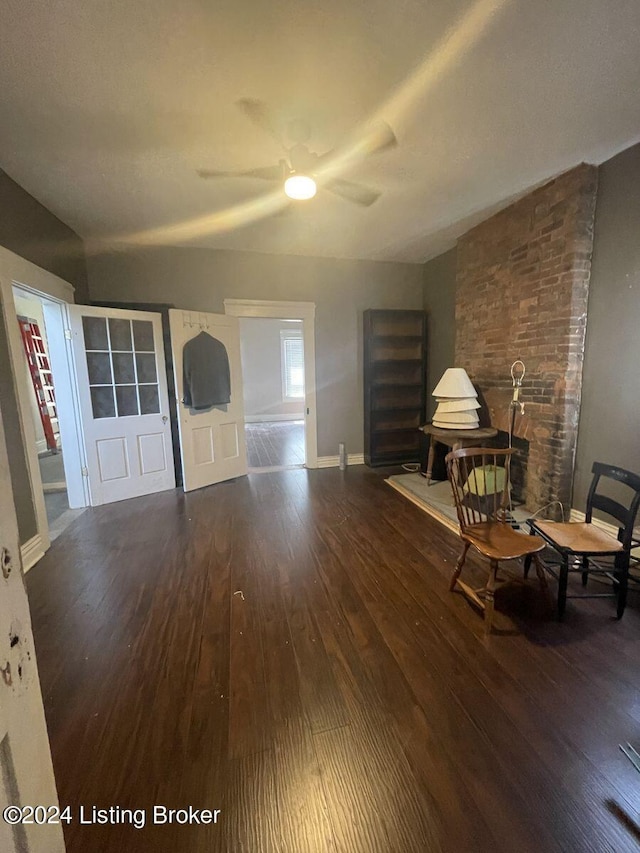 unfurnished living room featuring wood-type flooring, brick wall, and ceiling fan