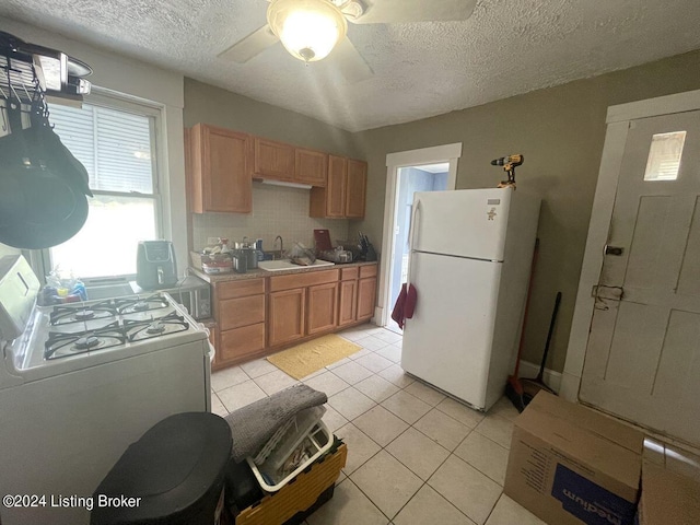 kitchen featuring light tile patterned flooring, white appliances, a textured ceiling, ceiling fan, and sink