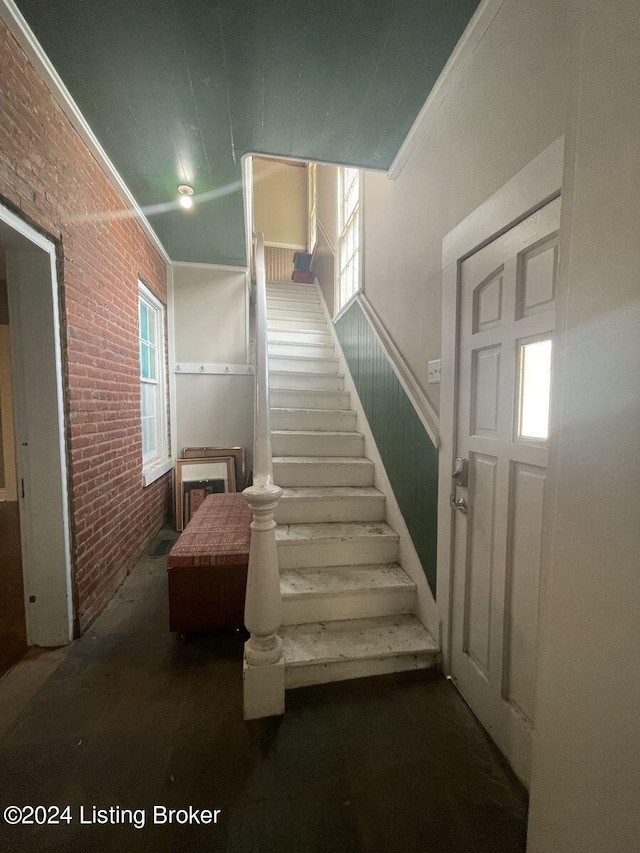 staircase with brick wall and ornamental molding