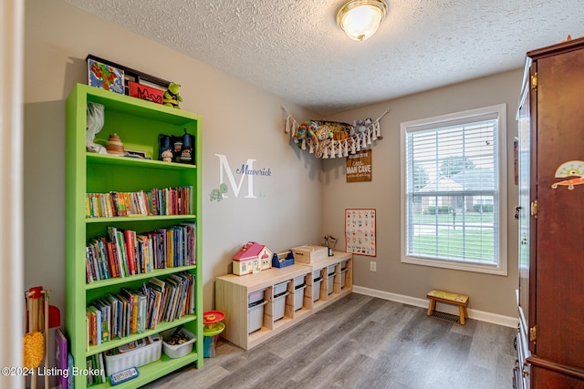 recreation room with a textured ceiling and hardwood / wood-style flooring