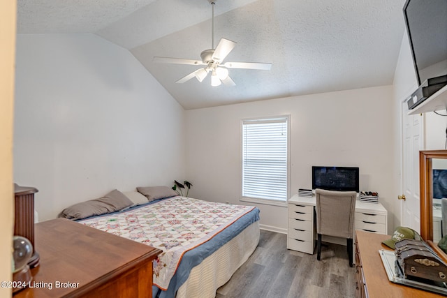 bedroom with ceiling fan, light hardwood / wood-style flooring, a textured ceiling, and lofted ceiling