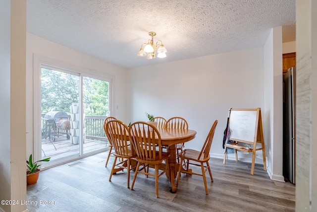 dining space with hardwood / wood-style floors, a textured ceiling, and a chandelier