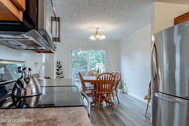 kitchen featuring a textured ceiling, stainless steel fridge, stove, an inviting chandelier, and wood-type flooring