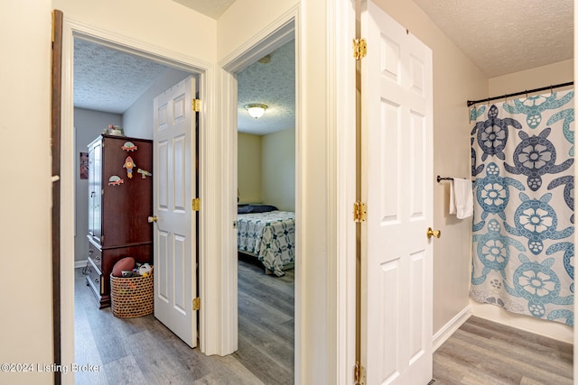 corridor featuring light hardwood / wood-style flooring and a textured ceiling