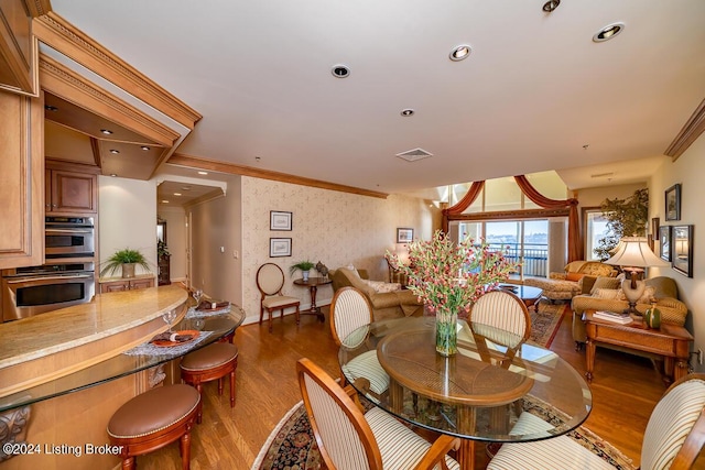 dining area with dark wood-type flooring, visible vents, crown molding, and wallpapered walls