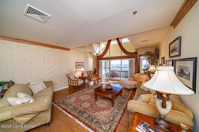 living area with wallpapered walls, visible vents, and crown molding