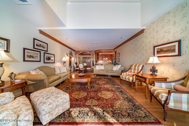 living room featuring wood finished floors, crown molding, and wallpapered walls