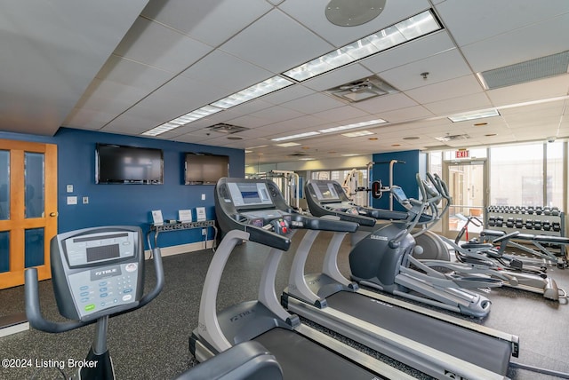 exercise room with a paneled ceiling and baseboards