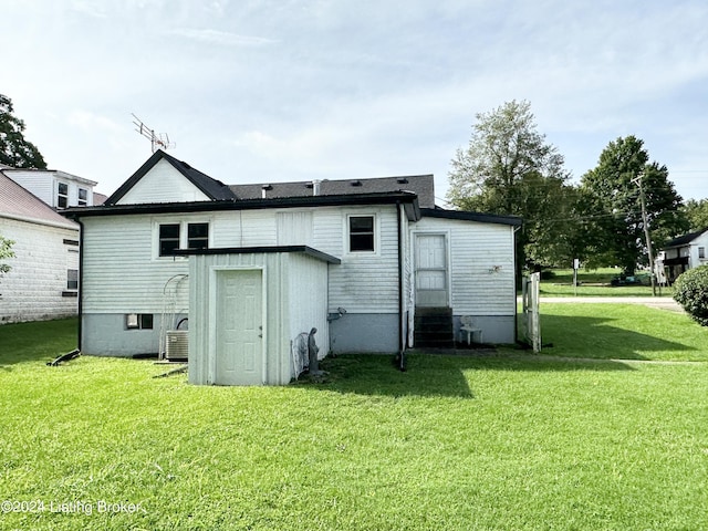 rear view of property featuring central AC and a lawn