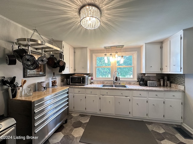 kitchen with white cabinetry, decorative light fixtures, sink, and tasteful backsplash